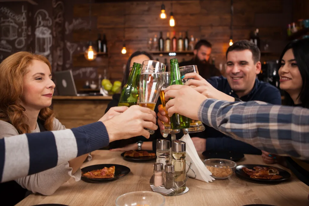 Group of happy friends drinking and toasting beer at brewery bar restaurant